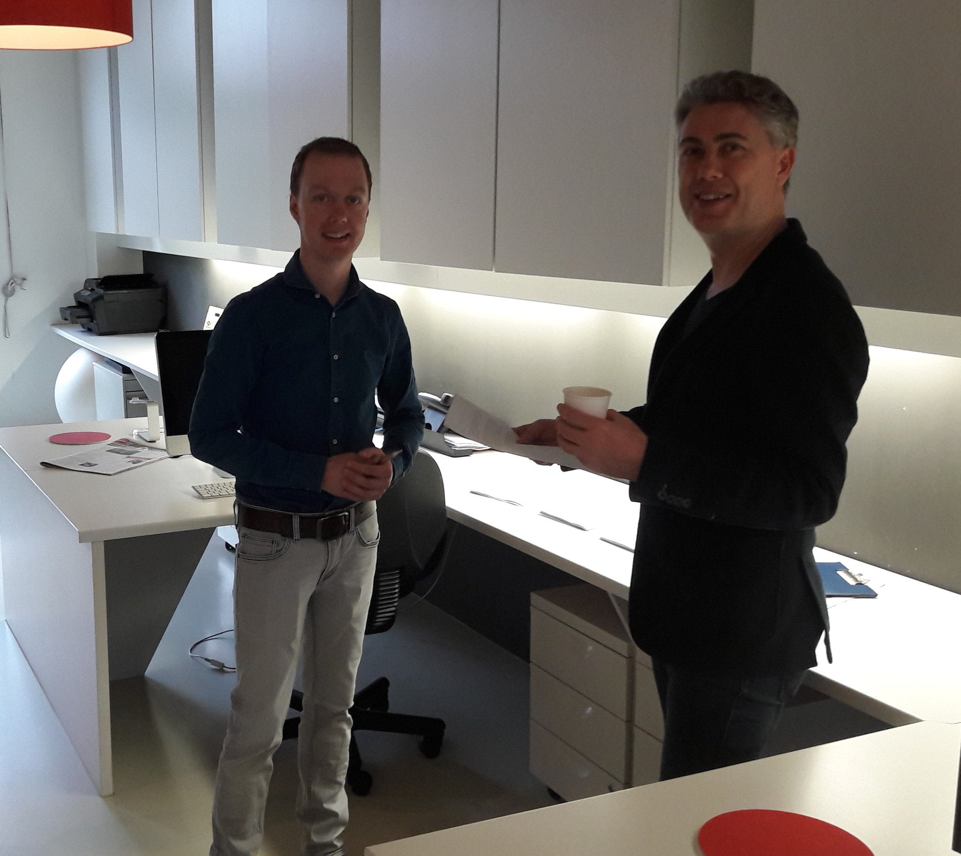 Twee mannen met koffie in modern kantoor.