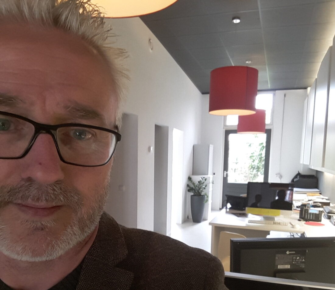 Man met bril in modern kantoorinterieur.