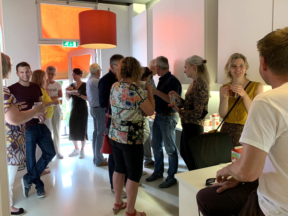 Netwerkevenement met mensen die praten en drankjes vasthouden.