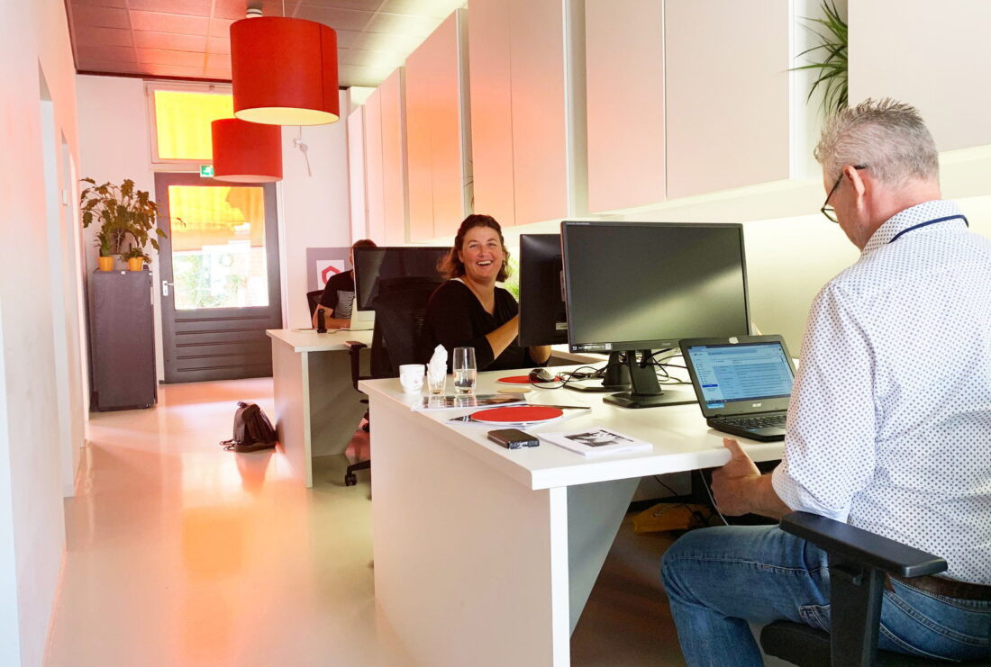 Twee collega's werkzaam op kantoor met computers.