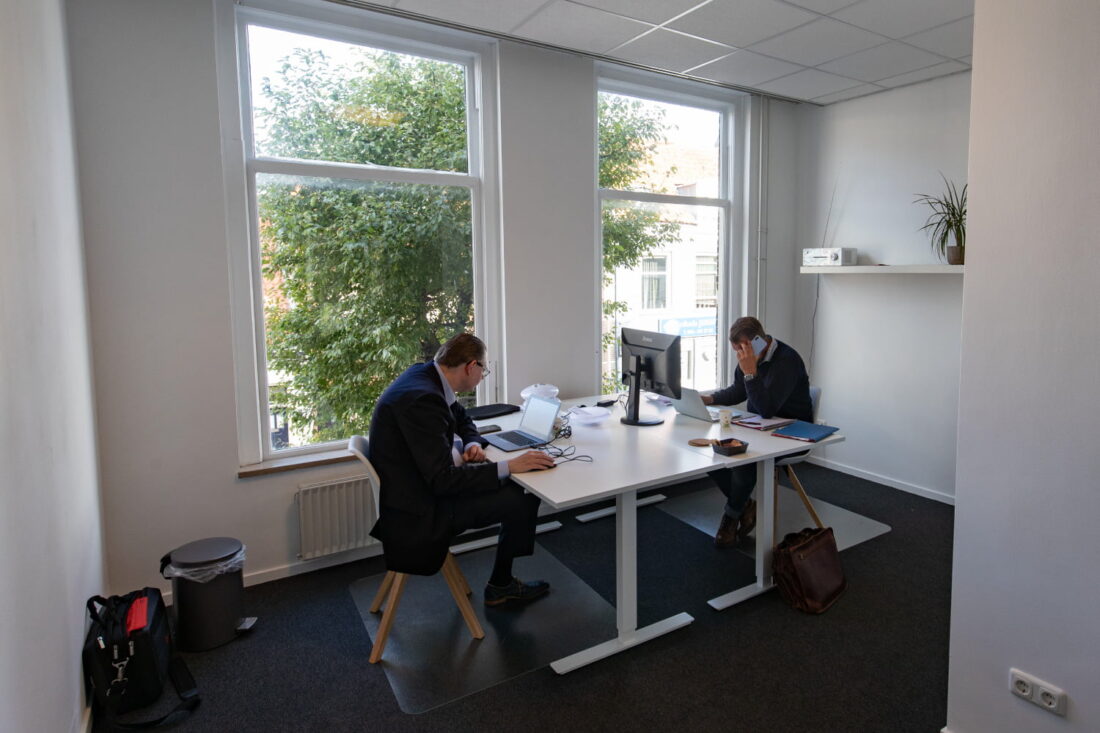 Twee personen werken geconcentreerd in een kantoorruimte.