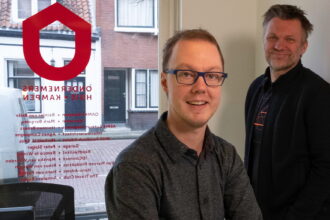 Twee mannen in kantoor met bedrijfslogo op raam.